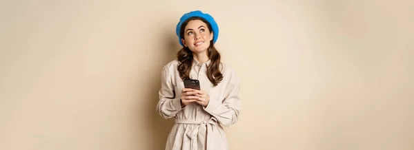 Dreamy Smiling Woman Stylish Trenchcoat Looking Fantasizing While Shopping Mobile —  Fotos de Stock