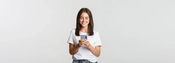 Sonriendo Chica Atractiva Usando Teléfono Móvil Mirando Pantalla Complacido —  Fotos de Stock