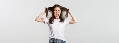 Öfkeli genç bir kadın saçlarını başını yoluyor ve kızgın bağırıyor..