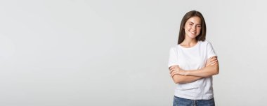 Kendinden emin çekici bir kadının portresi, çapraz kollar göğsü ve mutlu bir gülümseme..