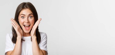 Heyecanlı, mutlu, esmer kızın yakın plan fotoğrafı. Şaşırmış görünüyor, el ele tutuşuyor, hayrete düşüyor..