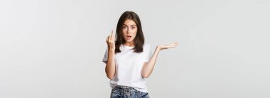 Confused and pissed-off brunette girl arguing about wedding, showing finger without ring.