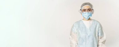 Portrait of doctor, female nurse in personal protective equipment, looking confident and professional, standing over white background.