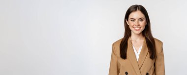 Portrait of business woman with enthusiastic face expression, smiling, looking confident, standing in suit over white background.