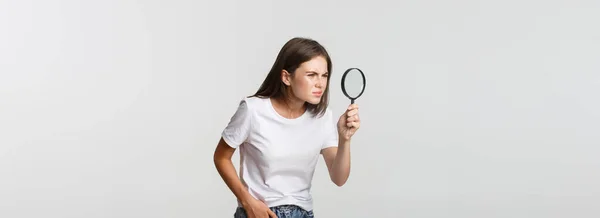 真面目で魅力的な若い女性が何かを探している 虫眼鏡を通して見て 白い背景 — ストック写真