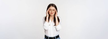 Corporate woman grimacing, touching head, feeling headache, severe migraine, standing over white background.