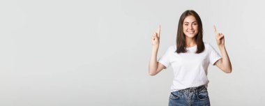 Çekici, gülümseyen esmer kız parmaklarını kaldırıp logoyu gösteriyor..