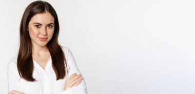 Kendine güvenen iş kadını, gülümseyen profesyonel girişimci, göğsünde çapraz kollar, beyaz arka planda duran coşkulu bir gülümseme..