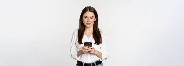 年轻女性 手持智能手机 面带微笑 看着相机 使用手机应用程序 手机技术和网上购物概念 白色背景 — 图库照片
