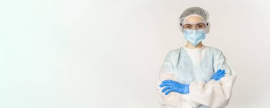 Professional doctor in personal protective equipment from coronavirus, cross arms on chest, looking confident, standing over white background.