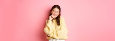 Tatlı, genç bir kadın gözlerini kapat ve gülümse, iltifattan kızaran, rüya gibi görünen, pembe arka planda duran. Boşluğu kopyala