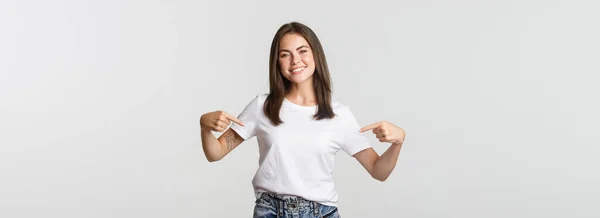 Atractiva Chica Morena Sonriente Apuntando Logotipo Mostrando Pancarta Centro —  Fotos de Stock