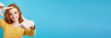 Çilli cheerfuly parmak ile kamera çerçeve yapma gülümseyen güzel zencefil Bayan portresi. Beyaz arka plan üzerinde izole. Kopya alanı