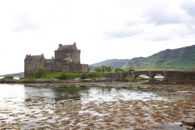 Eilean Donan şatosu İskoçya 'da. Köprüsü, dalgalı yamaçları, nehri ve Saint Andrews bayrağı görünüyor.. 