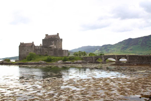 Eilean Donan şatosu İskoçya 'da. Köprüsü, dalgalı yamaçları, nehri ve Saint Andrews bayrağı görünüyor.. 