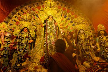 Kolkata, Hindistan - 8 Ekim 2019: Hindu rahip Durga 'ya kutsal dumanla tapıyor, aarti - kutsal Durga Puja festivali ritüeli. - Renkli ışığın altında çekilen.