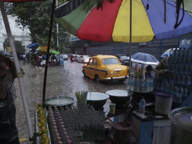 Kolkata, Batı Bengal, Hindistan - 16 Ağustos 2019: Arka planda muson yağmurları altında bir yol kenarı dükkânı ıslanıyor. Sarı taksi bekliyor. Kolkata 'nın yağışlı sezonu,
