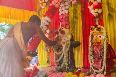Howrah, Batı Bengal, Hindistan - 29 Haziran 2020: Hindu rahip, Pandal 'ın içinde Tanrı Jagannath, Balaram ve Suvodra' ya tapındığı için, Tanrı Balaram putunun üzerine kutsal yajna külünü ayin olarak koydu..