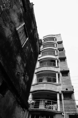 Yeni geliştirilmiş kentsel konutlara karşı ayakta duran eski konut binası, zıt siyah ve beyaz görüntü. Howrah, Batı Bengal, Hindistan.