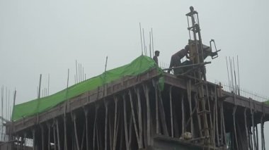 Howrah, West Bengal, India - 12th September 2021 : Casting of roof top of a high rise building. Cement is being carried up by an temporary elevator in the side of the wall. Sky background.