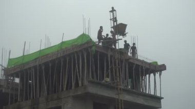 Howrah, West Bengal, India - 12th September 2021 : Casting of roof top of a high rise building. Cement is being carried up by an temporary elevator in the side of the wall. Indian labours working.
