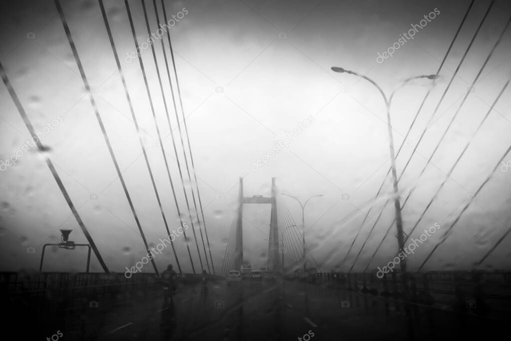 Vidyasagar Setu over river Ganges, known as 2nd Hooghly Bridge in Kolkata,West Bengal, India. Abstract black and white image shot aginst glass with raindrops all over it, Black and white.