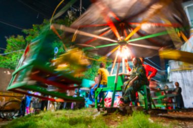 Howrah 'ın bulanık görüntüsü, Batı Bengal, Hindistan. Nagordola 'ya binen çocukları izleyen yaşlı bir kadın. Geleneksel bir eğlence gezisi. Gajan ya da Charak festivali, yavaş deklanşör hızıyla çekildi.
