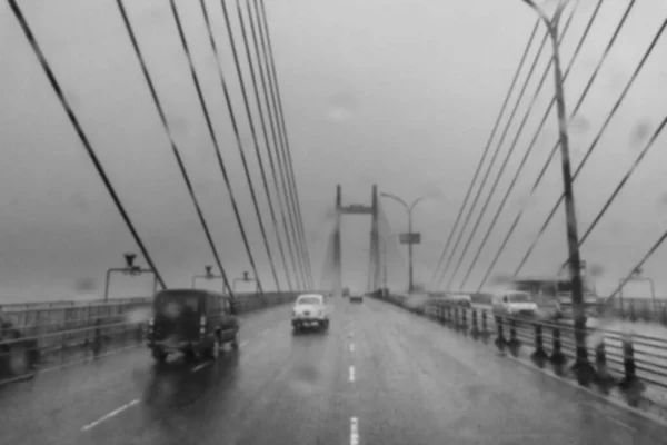 Blurred image of Howrah, West Bengal, India. Image shot through raindrops falling on car windshield , wet glass, traffic at 2nd Hoogly bridge. Monsoon black and white stock image.