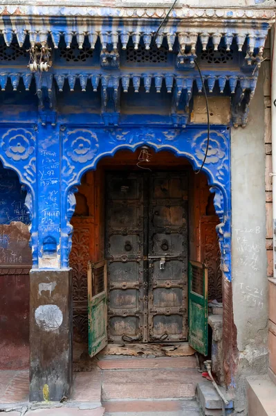 Traditional wooden door and blue coloured house of Jodhpur city, Rajsthan, India. Historically, Hindu Brahmins used to paint their houses in blue for being upper caste, the tradition follows.