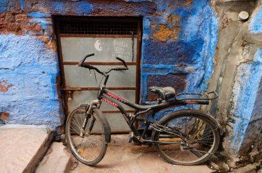Jodhpur, Rajasthan, Hindistan - 21 Ekim 2019: Geleneksel renkli evler. Tarihsel olarak, Hindu Brahmanlar üst kasttan oldukları için evlerini maviye boyarlardı. Bir bisiklet önde tutulur..