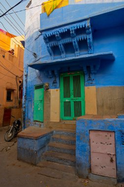 Jodhpur, Rajasthan, Hindistan - 21 Ekim 2019: Geleneksel Mavi renkli ev, yeşil kapı. Hindu Brahmanlar evlerini üst kasttan oldukları için maviye boyarlardı, gelenek böyle devam eder..