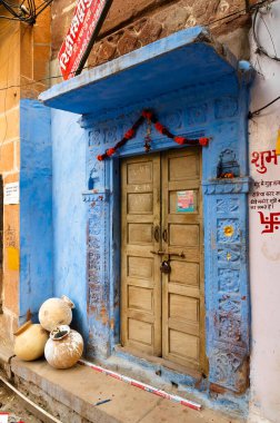 Jodhpur, Rajasthan, Hindistan - 21 Ekim 2019: Geleneksel ahşap kapı ve mavi renkli ev. Hindu Brahmanlar evlerini üst kasttan oldukları için maviye boyarlardı, gelenek böyle devam eder..