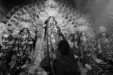 Kolkata, Batı Bengal, Hindistan - 7 Ekim 2019: Hindu rahip Durga 'ya kutsal dumanla sondhipujo aarti sırasında kutsal pradip ile tapıyor. Siyah ve beyaz.