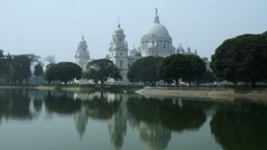 Kolkata 'da bulunan Victoria Memorial adlı büyük bir mermer bina, Batı Bengal, Kolkata' daki en ünlü anıtlardan biridir. Ön plandaki göl suyunun yansıması. Uzaklaş..