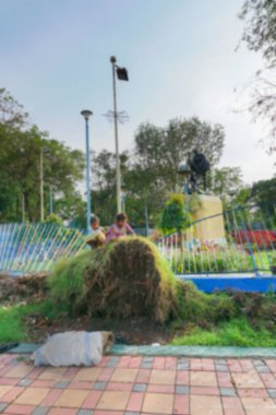 Kolkata 'nın bulanık görüntüsü, Batı Bengal, Hindistan. İki kızın bulanık görüntüsü ağaçta oynuyor. Kasırga Amphan tarafından sökülmüş, Mahatma Gandhi heykelinin önünde. Yıkımdan sonraki hayat.
