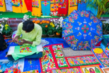 Kolkata 'nın bulanık görüntüsü, Batı Bengal, Hindistan. Genç Bengalli ressam Pattachitra ya da Patachitra 'yı resmediyor - geleneksel, kumaş tabanlı parşömen tablosu. El sanatları fuarında satılık..