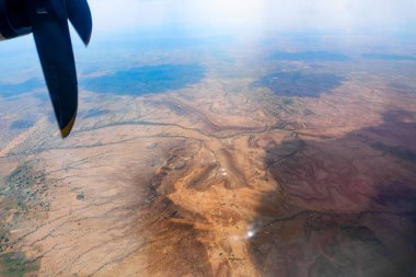 Hindistan, Rajasthan 'daki bir uçaktan Thar Çölü manzarası. Çerçevedeki pervaneler ve çöl. Aşağıdaki çölde güneş ışığı ve bulutların gölgesi.