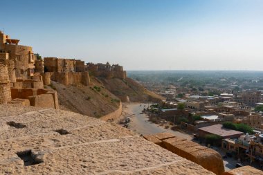 Jaisalmer, Rajasthan, Hindistan - 13 Ekim 2019: Jaisalmer Kalesi veya Altın Kale 'nin büyük duvarları, sarı kumtaşından yapılmış, sabah ışığında şehrin bir kısmı çerçevede. UNESCO dünya mirası sahası.