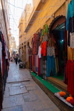 Jaisalmer, Rajasthan, Hindistan - 13 Ekim 2019: Jaisalmer Kalesi 'nin içindeki pazar yerinde sabah vakti renkli giysiler satılıyor. Thar Çölündeki UNESCO dünya mirası sahası.