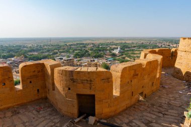 Jaisalmer, Rajasthan, Hindistan - 13 Ekim 2019: Jaisalmer Kalesi ya da Sonar Quila ya da Altın Kale 'nin büyük duvarları, sarı kumtaşından yapılmış, arka planda şehir olan sabah ışığı. UNESCO sitesi.