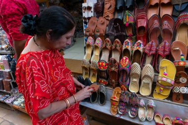 Jaisalmer, Rajasthan, Hindistan - 13 Ekim 2019: Hintli kadın Rajasthani kadınlarının ayakkabılarını satılığa çıkarıyor. Jaisalmer, Rajasthan, Hindistan.