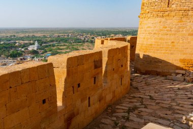 Jaisalmer, Rajasthan, Hindistan - 13 Ekim 2019: Jaisalmer Kalesi ya da Sonar Quila ya da Altın Kale 'nin büyük duvarları, sarı kumtaşından yapılmış, arka planda şehir olan sabah ışığı. UNESCO sitesi.
