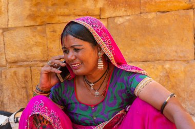 Jaisalmer, Rajasthan, Hindistan - 13 Ekim 2019: Rajasthani kadını cep telefonuyla konuşurken gülümsüyor Jaisalmer Kalesi 'nin içinde. Jaisalmer 'in mutlu kadını.