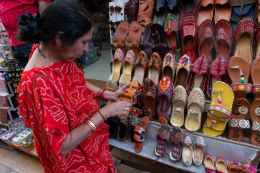 Jaisalmer, Rajasthan, Hindistan - 13 Ekim 2019: Hintli kadın Rajasthani kadınlarının ayakkabılarını satılığa çıkarıyor. Jaisalmer, Rajasthan, Hindistan.