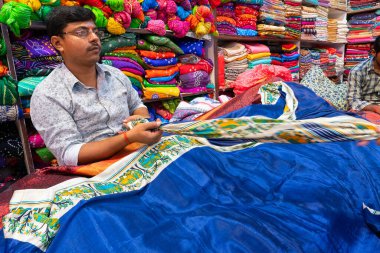 Jaisalmer, Rajasthan, Hindistan - 15 Ekim 2019: Sari satıcı müşterilere sari satıyor, güzel renkli Hint sarileri pazar yeri Jaisalmer, Hindistan 'da satışa sunuluyor.