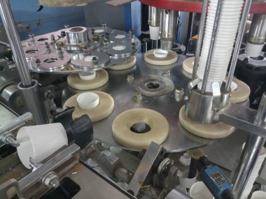 Kolkata, Batı Bengal, Hindistan - 17 Mayıs 2019: Kağıt bardaklar kağıt bardak üretim makineleri kullanılarak kağıttan yapılıyor, çalışan bir bardak imalatı veya üretim ünitesinin iç görünümü.