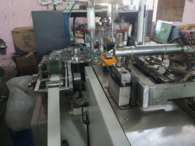 Kolkata, Batı Bengal, Hindistan - 17 Mayıs 2019: Kağıt bardaklar kağıt bardak üretim makineleri kullanılarak kağıttan yapılıyor, çalışan bir bardak imalatı veya üretim ünitesinin iç görünümü.