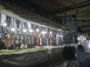 Kolkata, Batı Bengal, Hindistan - 16 Ağustos 2019: Yeni pazar alanında, yağmur altında yol kenarındaki giyim mağazalarının önünden geçen yayalar. Kolkata 'da muson yağmurları,