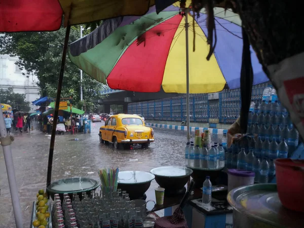 Kolkata, Batı Bengal, Hindistan - 16 Ağustos 2019: Arka planda muson yağmurları altında bir yol kenarı dükkânı ıslanıyor. Sarı taksi bekliyor. Kolkata 'nın yağışlı sezonu,