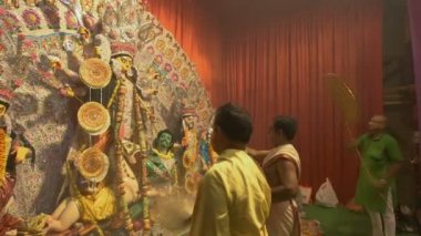 Kolkata, Hindistan - 13 Ekim 2021: Hindu rahipler Tanrıça Durga 'ya panchpradip, kutsal lamba, chamor ve el vantilatörü ile tapıyorlar. Ashtami puja aarati - kutsal Durga Puja ritüeli - gece çekildi. 4K video.